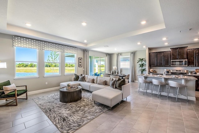 living room featuring a tray ceiling and a textured ceiling