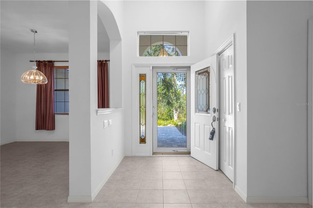 foyer with a towering ceiling, light tile patterned floors, and a notable chandelier