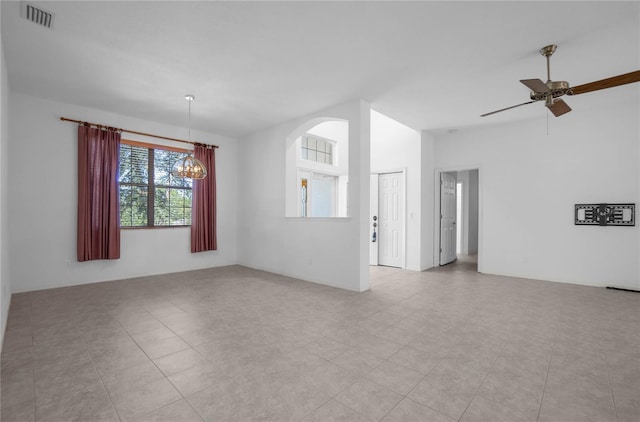 empty room with ceiling fan with notable chandelier, light tile patterned flooring, and lofted ceiling