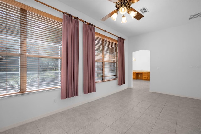 tiled spare room featuring ceiling fan and a healthy amount of sunlight