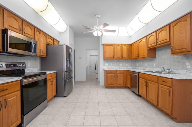 kitchen featuring sink, decorative backsplash, ceiling fan, light tile patterned floors, and appliances with stainless steel finishes