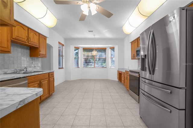 kitchen with ceiling fan, sink, stainless steel appliances, backsplash, and pendant lighting