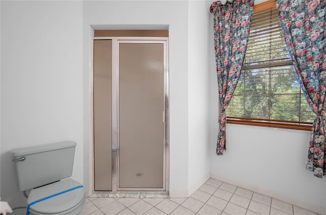 bathroom featuring toilet, tile patterned floors, and a shower with door