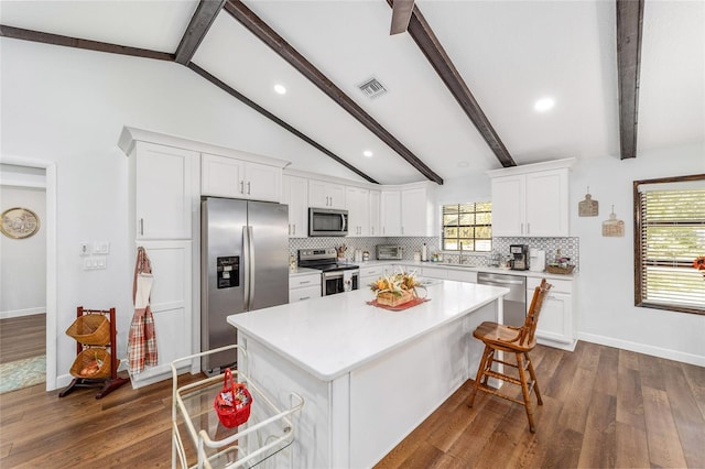 kitchen featuring white cabinets, a center island, lofted ceiling with beams, and stainless steel appliances