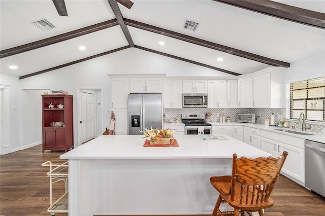 kitchen with sink, a center island, stainless steel appliances, decorative backsplash, and a breakfast bar