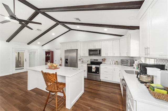 kitchen with white cabinetry, a center island, stainless steel appliances, tasteful backsplash, and vaulted ceiling with beams