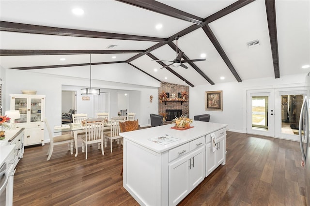 kitchen with a brick fireplace, pendant lighting, white cabinetry, dark hardwood / wood-style floors, and a kitchen island