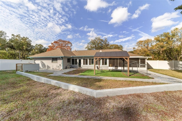 single story home featuring a sunroom, solar panels, and a front yard