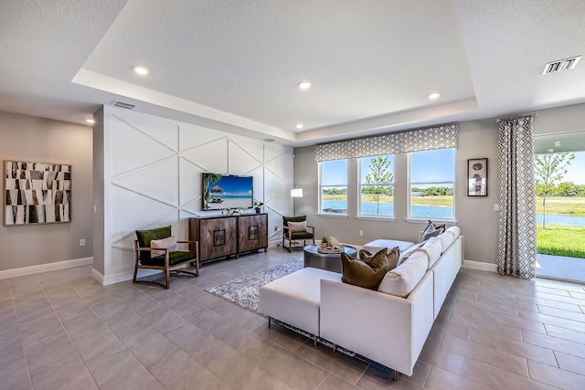 living room featuring light tile patterned flooring, a textured ceiling, and a tray ceiling