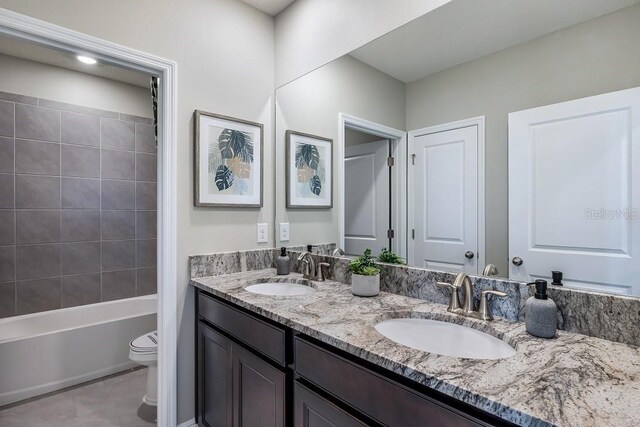 full bathroom featuring tile patterned floors, vanity, toilet, and tiled shower / bath combo