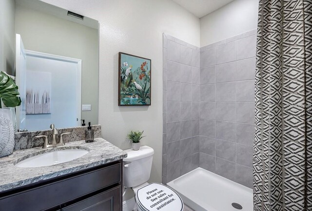 bathroom featuring vanity, toilet, and tiled shower