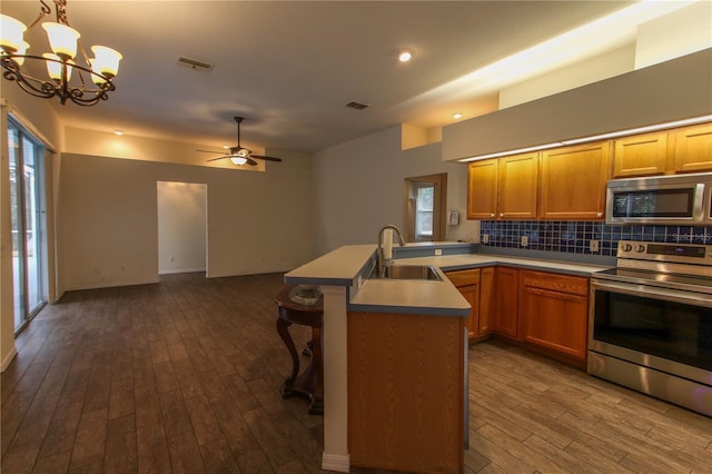 kitchen featuring sink, stainless steel appliances, dark hardwood / wood-style flooring, pendant lighting, and ceiling fan with notable chandelier