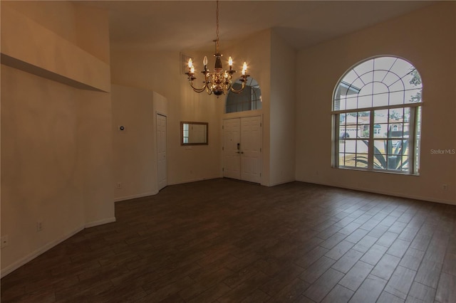 interior space featuring a chandelier, a towering ceiling, and dark wood-type flooring