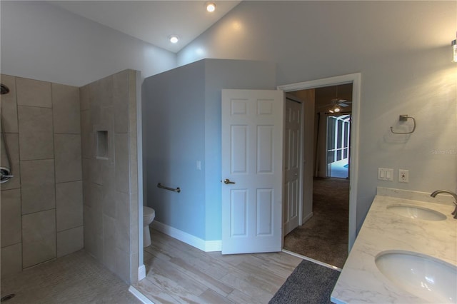 bathroom with hardwood / wood-style floors, vanity, vaulted ceiling, toilet, and a tile shower