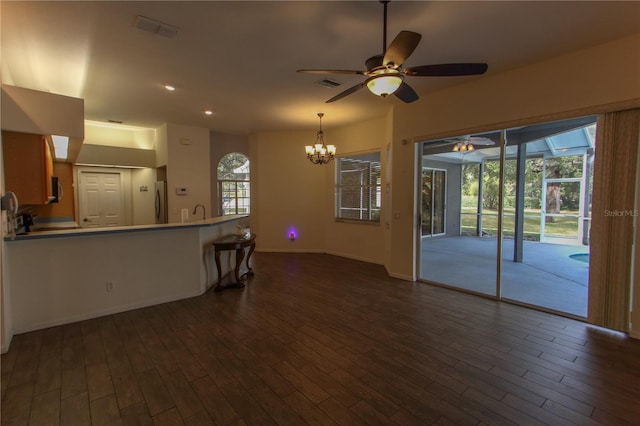 unfurnished living room with ceiling fan with notable chandelier and dark hardwood / wood-style floors