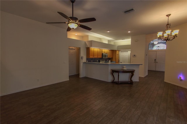 kitchen featuring kitchen peninsula, decorative backsplash, ceiling fan with notable chandelier, dark hardwood / wood-style floors, and a breakfast bar area