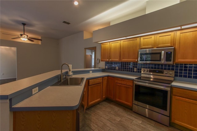 kitchen featuring ceiling fan, sink, dark wood-type flooring, kitchen peninsula, and appliances with stainless steel finishes