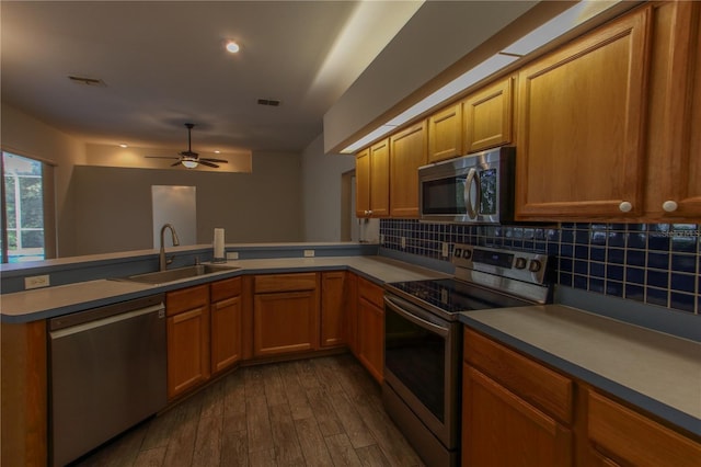 kitchen featuring ceiling fan, sink, dark wood-type flooring, backsplash, and appliances with stainless steel finishes