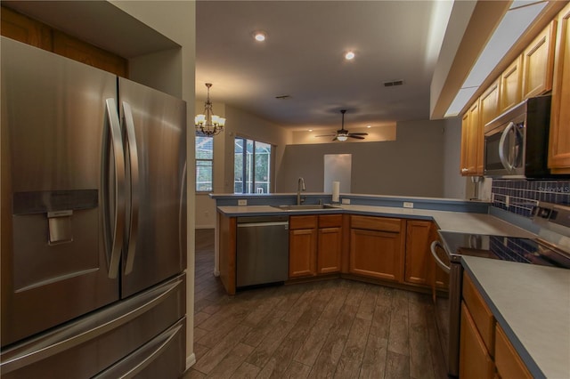 kitchen featuring ceiling fan with notable chandelier, dark hardwood / wood-style floors, sink, and stainless steel appliances