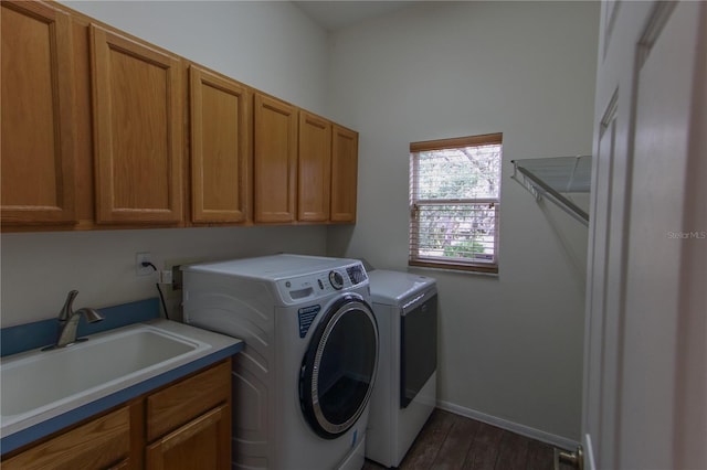 clothes washing area featuring separate washer and dryer, dark hardwood / wood-style flooring, cabinets, and sink