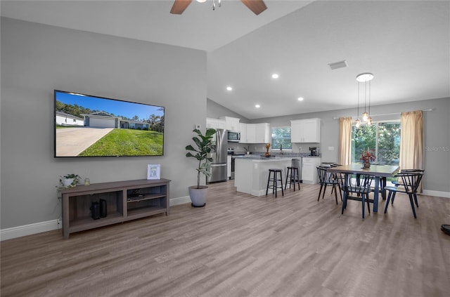 dining room featuring ceiling fan, high vaulted ceiling, and light hardwood / wood-style floors