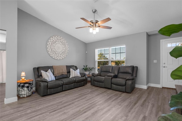 living room with ceiling fan, light hardwood / wood-style floors, and vaulted ceiling