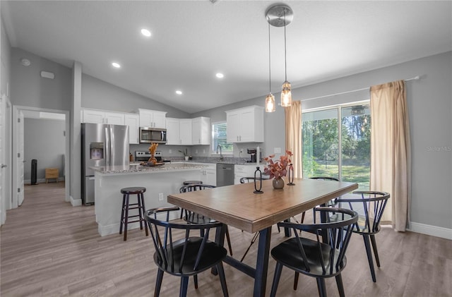 dining room featuring plenty of natural light, light hardwood / wood-style floors, lofted ceiling, and sink