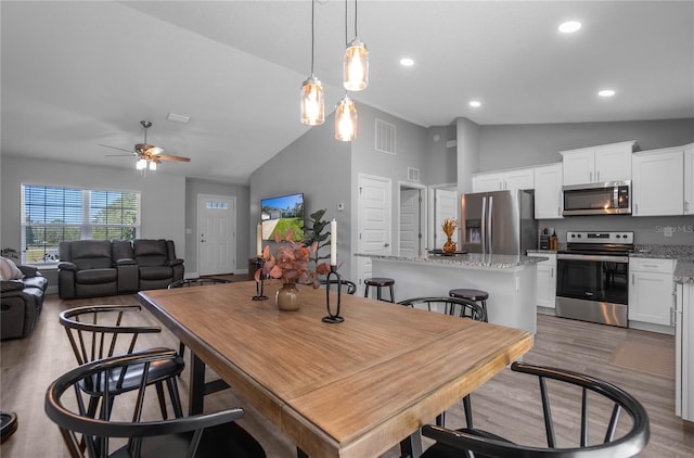 dining space with ceiling fan, high vaulted ceiling, and wood-type flooring