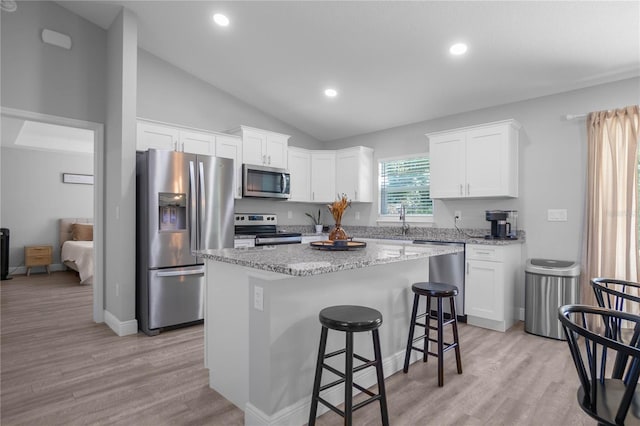 kitchen featuring a center island, vaulted ceiling, light wood-type flooring, appliances with stainless steel finishes, and white cabinetry