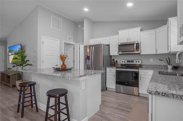 kitchen featuring sink, stainless steel appliances, a kitchen island, light hardwood / wood-style floors, and white cabinets