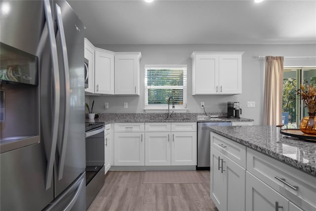 kitchen with sink, white cabinets, stainless steel appliances, and light hardwood / wood-style flooring