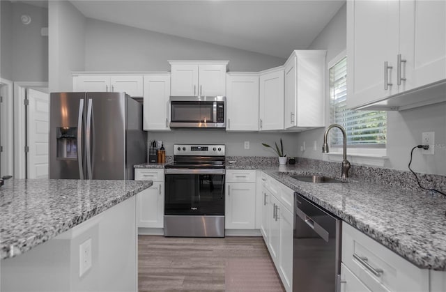 kitchen with white cabinets, appliances with stainless steel finishes, vaulted ceiling, and sink