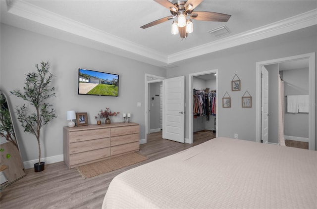 bedroom featuring hardwood / wood-style floors, a walk in closet, ceiling fan, ornamental molding, and a closet