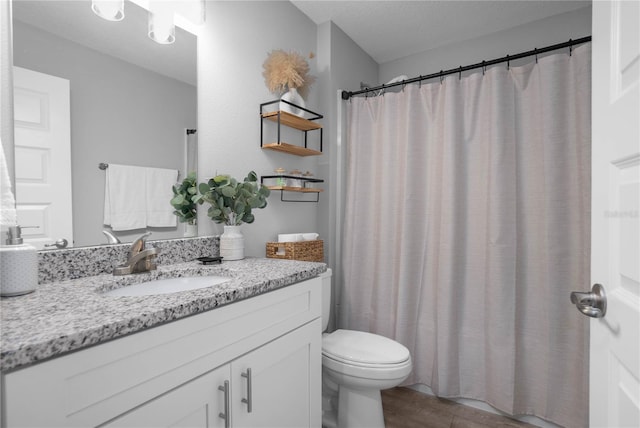 bathroom with hardwood / wood-style flooring, vanity, toilet, and a textured ceiling