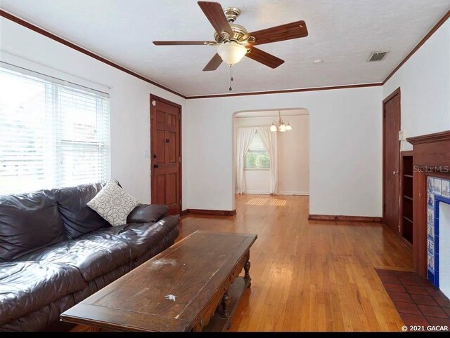 living room featuring ornamental molding, ceiling fan with notable chandelier, and hardwood / wood-style flooring