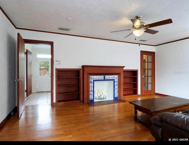 unfurnished living room with french doors, ornamental molding, a textured ceiling, ceiling fan, and light hardwood / wood-style flooring