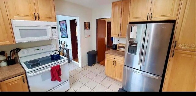 kitchen with light brown cabinets, light tile patterned floors, and white appliances