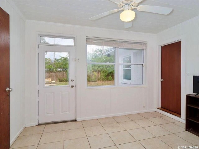 doorway to outside with ceiling fan, light tile patterned floors, and crown molding