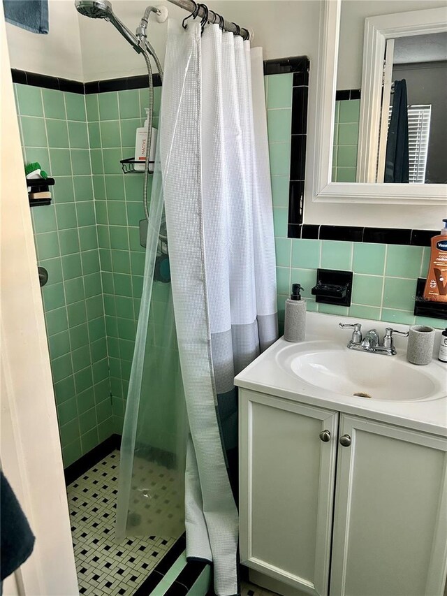 bathroom featuring vanity, tile patterned flooring, tile walls, tasteful backsplash, and a tile shower