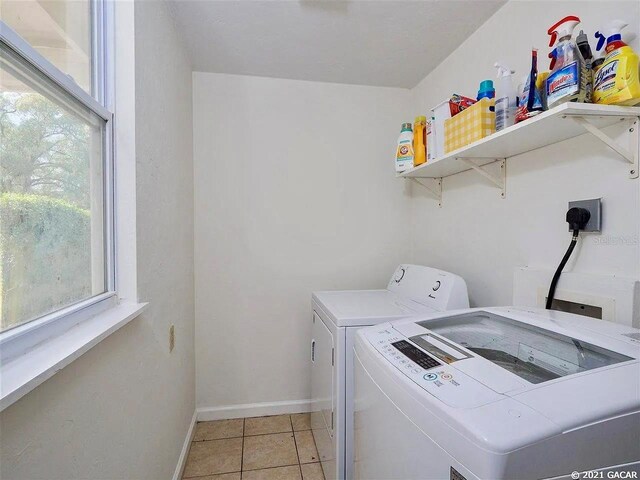 washroom with light tile patterned floors and washing machine and dryer