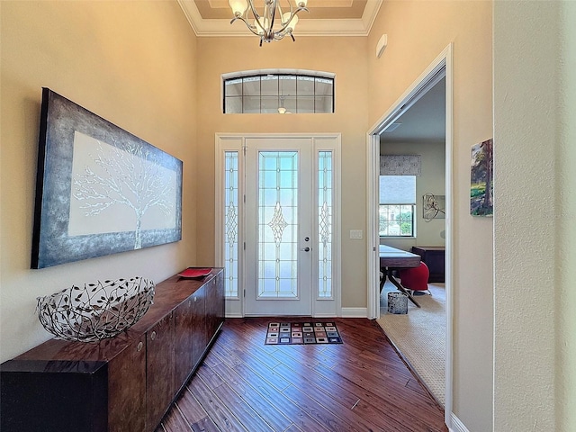 entrance foyer with dark hardwood / wood-style floors, ornamental molding, and a chandelier