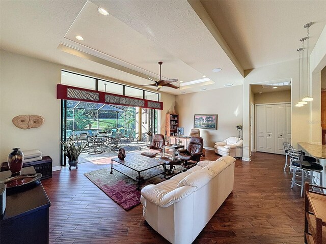 living room featuring a tray ceiling, ceiling fan, a textured ceiling, and dark hardwood / wood-style floors