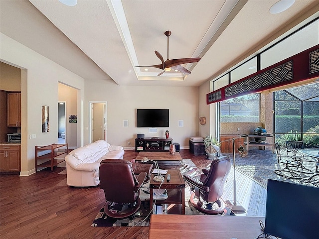 living room with a tray ceiling, ceiling fan, and dark hardwood / wood-style floors