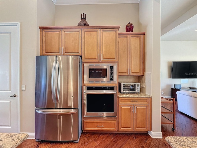 kitchen featuring ornamental molding, light stone countertops, stainless steel appliances, and dark wood-type flooring