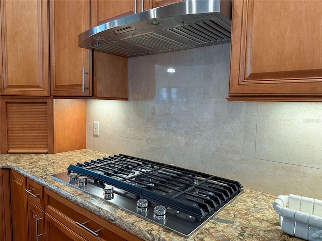 kitchen featuring decorative backsplash, black gas stovetop, light stone counters, and extractor fan