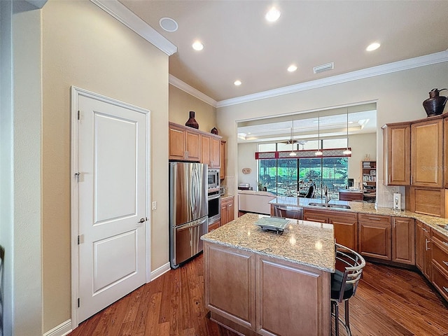 kitchen featuring appliances with stainless steel finishes, dark hardwood / wood-style flooring, a kitchen breakfast bar, crown molding, and a kitchen island