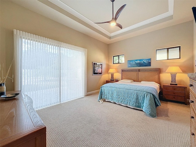 carpeted bedroom with access to exterior, a tray ceiling, and ceiling fan