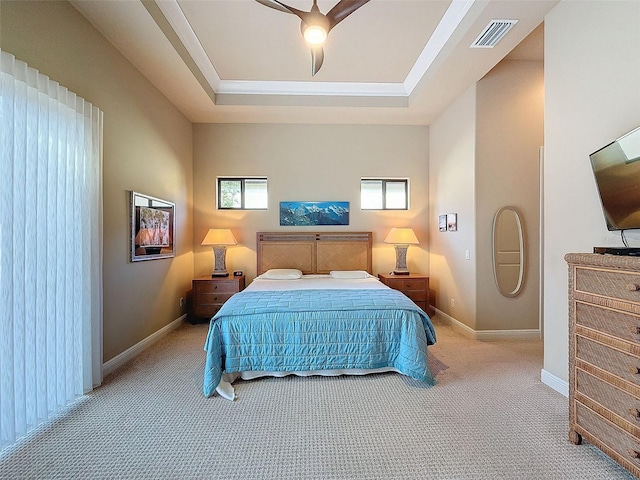 carpeted bedroom with a tray ceiling and ceiling fan