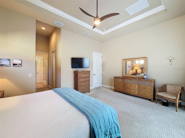 bedroom featuring ceiling fan, light carpet, a high ceiling, and a tray ceiling