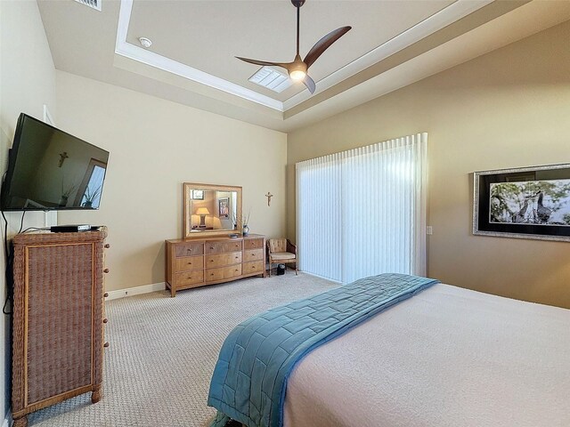 carpeted bedroom featuring ceiling fan and a tray ceiling